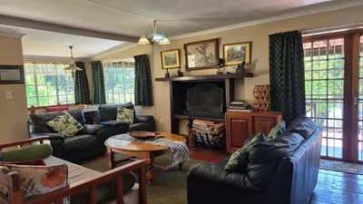 a living room with couches and a tv at Apple Blossom Cottage in Dullstroom