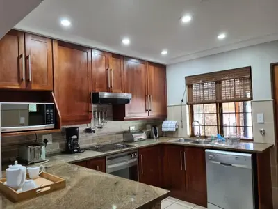 a kitchen with wooden cabinets and a counter top at Kruger Park Lodge Unit No. 267 with private pool in Hazyview