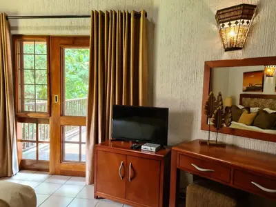 a living room with a television and a mirror at Kruger Park Lodge Unit No. 267 with private pool in Hazyview