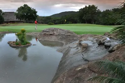 a man standing on a golf course next to a pond at Kruger Park Lodge Unit No. 267 with private pool in Hazyview
