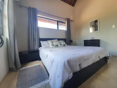 a bedroom with a large bed with a window at Kanimambo Chalet in Marloth Park