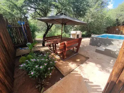 a picnic table with an umbrella next to a pool at Kanimambo Chalet in Marloth Park