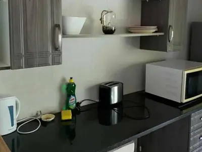 a kitchen with a black counter top with a microwave at Kanimambo Chalet in Marloth Park