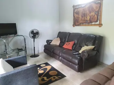 a living room with a black leather couch and a rug at Kanimambo Chalet in Marloth Park