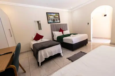 a hotel room with two beds and a table at Mandulia Guest House in Nelspruit