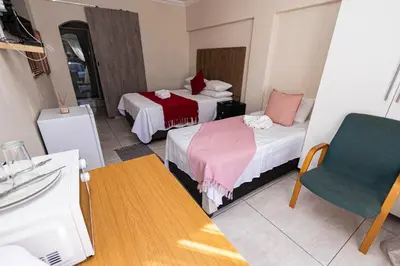 a hotel room with two beds and a chair at Mandulia Guest House in Nelspruit