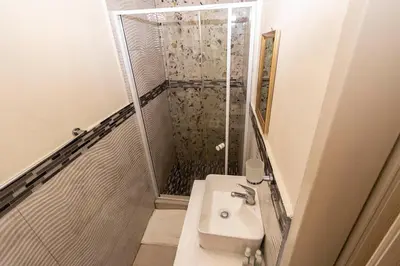 a white bathroom with a shower and a sink at Mandulia Guest House in Nelspruit