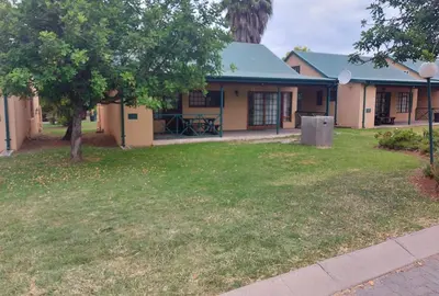 a house with a green yard with a tree at Pendleberry Holiday Resort - Unit 40 in Bela-Bela