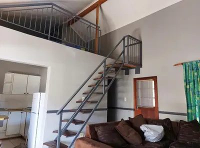 a staircase in a living room with a couch at Pendleberry Holiday Resort - Unit 40 in Bela-Bela
