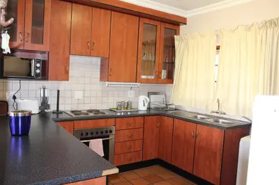 a kitchen with wooden cabinets and a black counter top at Phil's Place in Dullstroom