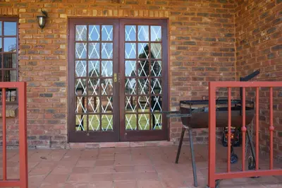 a glass door with a grill in front of a brick wall at Phil's Place in Dullstroom