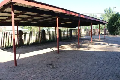 an empty parking lot with awning and a fence at Phil's Place in Dullstroom