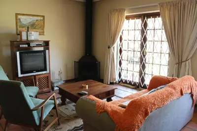 a living room with a couch and a table and a tv at Phil's Place in Dullstroom
