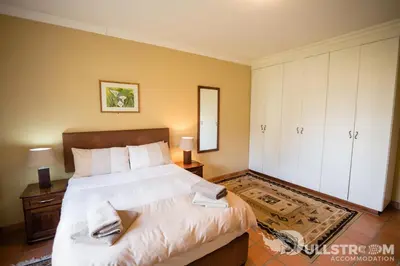 a bedroom with a large bed with white sheets at Phil's Place in Dullstroom