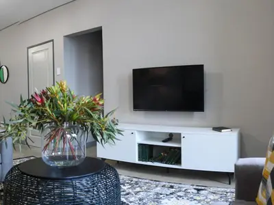 a living room with a television on a white entertainment center at Next To Apartment Hotel in Pretoria