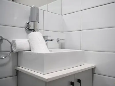 a white bathroom with a sink and a mirror at Next To Apartment Hotel in Pretoria