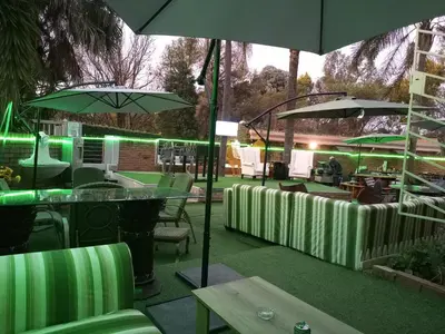 a patio with green chairs and tables and umbrellas at Menlyn Mews Guesthouse in Pretoria