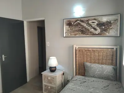 a bedroom with a bed and a lamp on a night stand at Menlyn Mews Guesthouse in Pretoria