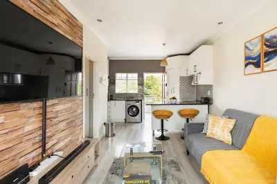 a living room with a couch and a kitchen at Sunset View Apartment with Free Secure Parking in Central Location in Centurion