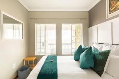 a bedroom with a white bed with green pillows at Sunset View Apartment with Free Secure Parking in Central Location in Centurion