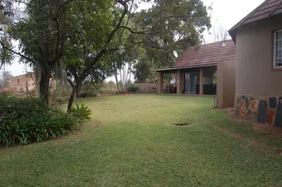 an empty yard next to a house with a tree at Nita's Air Bed & Breakfast & self catering in Crocodile Valley Estates