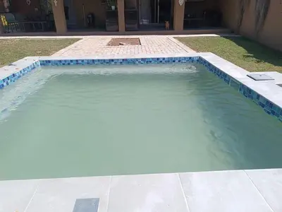 a swimming pool with blue tiles in a yard at Nita's Air Bed & Breakfast & self catering in Crocodile Valley Estates