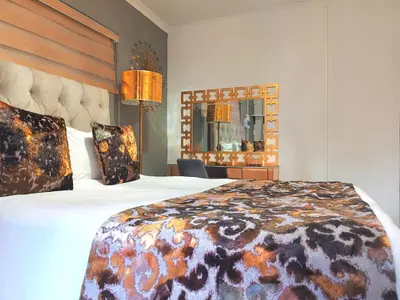 a hotel room with a large bed and a mirror at Homes of Ace Gold in Pretoria