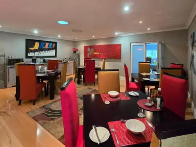 a dining room with tables and red chairs at Sunrise Serenity Guest House in Lydenburg