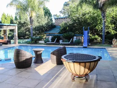 a swimming pool with a table and chairs next to a swimming pool at Sunrise Serenity Guest House in Lydenburg