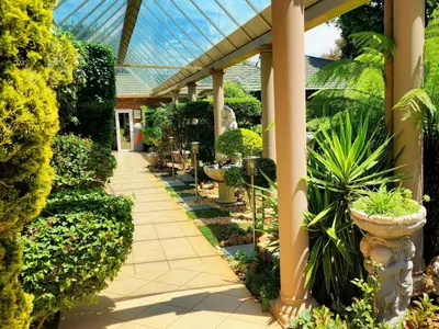 a greenhouse with plants and a walkway in a garden at Sunrise Serenity Guest House in Lydenburg