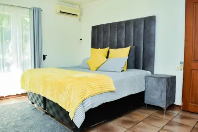 a bedroom with a large bed with yellow pillows at MTH in Nelspruit