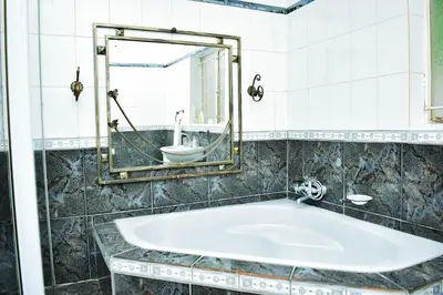 a bathroom with a tub with a mirror and a sink at MTH in Nelspruit