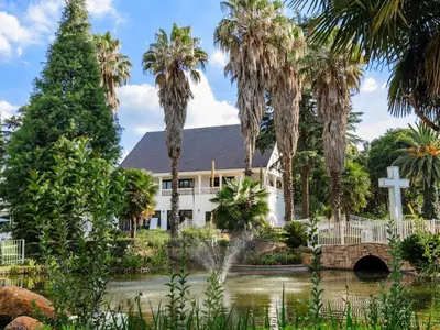 a church with palm trees and a bridge over a pond at Gracia de Dios in Benoni