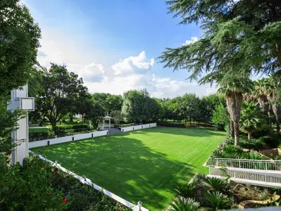 a large lawn with a white fence and trees at Gracia de Dios in Benoni