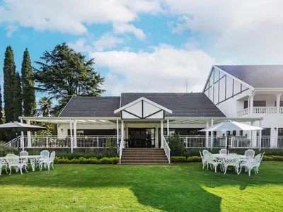 a white house with white chairs on the lawn at Gracia de Dios in Benoni