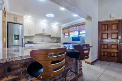 a kitchen with wooden stools at a counter at Kruger Park Lodge Unit No. 547 in Hazyview