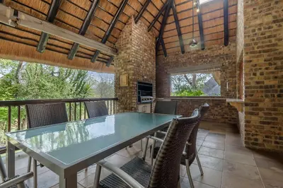 a dining room with a glass table and chairs at Kruger Park Lodge Unit No. 547 in Hazyview
