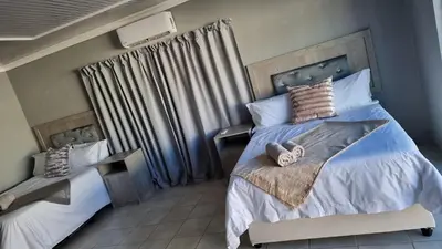 a bedroom with two beds and a window with curtains at The Unit Party House in eNyalungu
