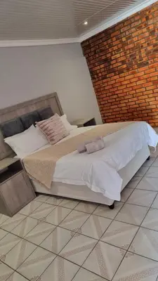 a bedroom with a large bed and a brick wall at The Unit Party House in eNyalungu