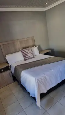 a bedroom with a large bed with white sheets at The Unit Party House in eNyalungu
