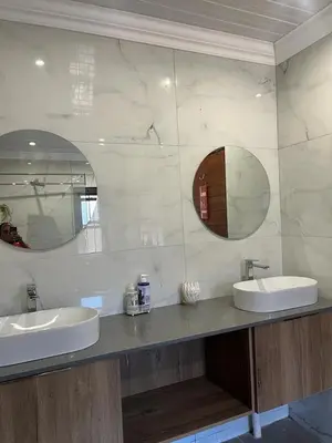 a bathroom with two sinks and two mirrors at Pine View Guesthouse Graskop in Graskop
