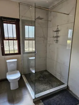 a bathroom with a toilet and a glass shower at Pine View Guesthouse Graskop in Graskop
