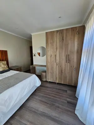 a bedroom with a bed and wooden cabinets at Pine View Guesthouse Graskop in Graskop