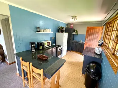 a kitchen with a table and a blue wall at The Hedge at Dullstroom Cottage in Dullstroom