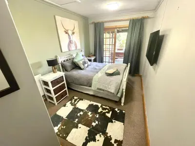 a small bedroom with a bed and a rug in it at The Hedge at Dullstroom Cottage in Dullstroom