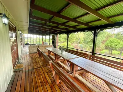 a porch with wooden benches on a building at The Hedge at Dullstroom Cottage in Dullstroom