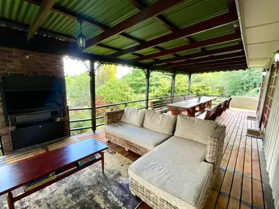 a screened in porch with a couch and a tv at The Hedge at Dullstroom Cottage in Dullstroom