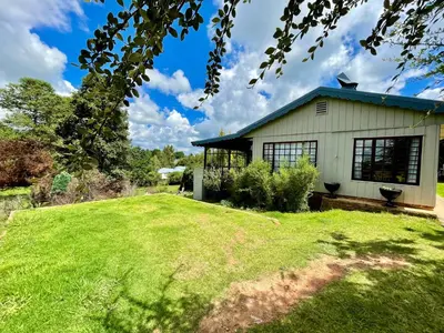 a house with a green lawn in front of it at The Hedge at Dullstroom Cottage in Dullstroom