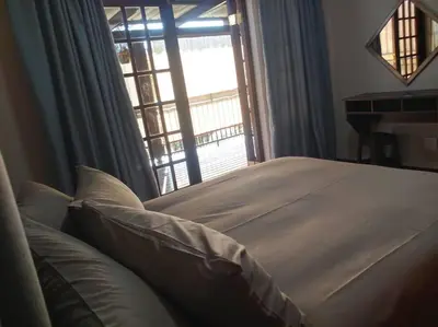 a bedroom with a bed and a large window at Ebeneezer Self-Catering Guesthouse in the Lowveld in Sabie