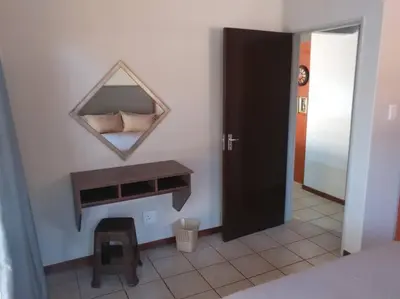 a bedroom with a mirror on the wall and a table at Ebeneezer Self-Catering Guesthouse in the Lowveld in Sabie